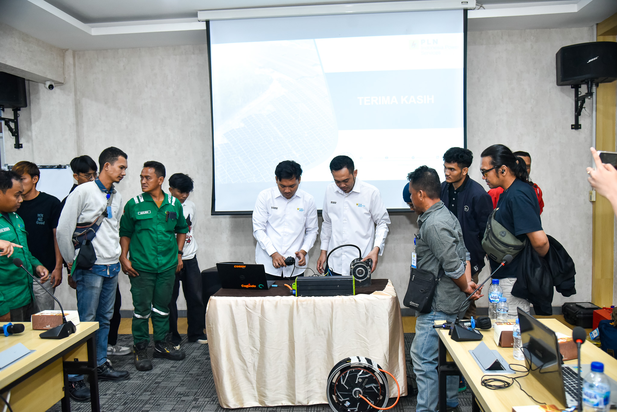 Peserta sosialisasi di UBP Priok memeriksa baterai dan penggerak motor listrik, dengan identitas PLN IP Services pada pakaian tim serta nama Cogindo dan Cogen pada peralatan. Foto dokumentasi resmi PLN IP Services, diunggah 7 Oktober 2026.